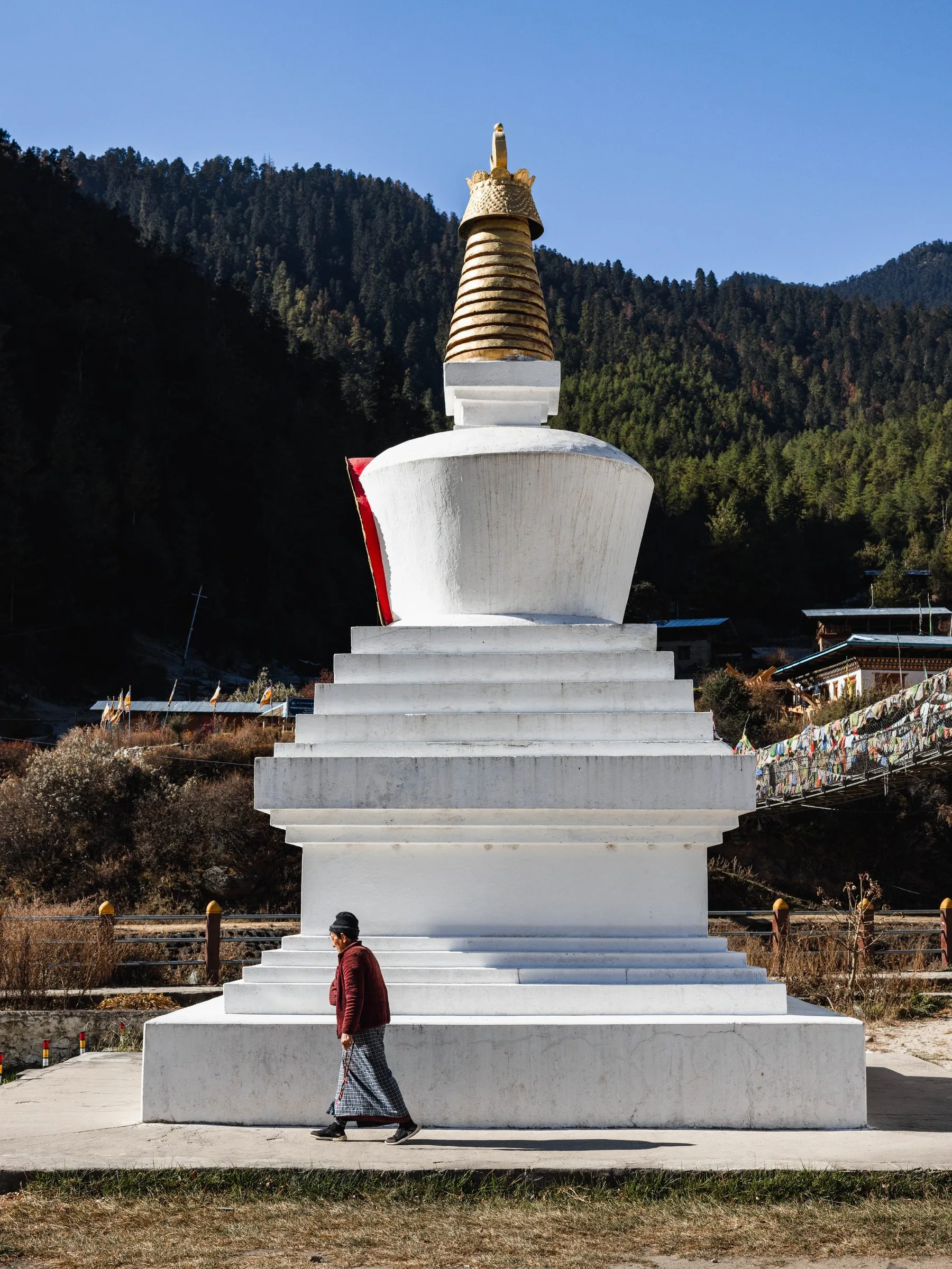 Walking past a white chorten in a Bhutanese valley during the arrival and immersion days