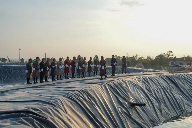 Officials in traditional dress standing along the lined edge of a new reservoir