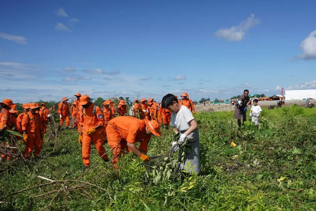 Volunteers and schoolchildren clearing land together at the Gelephu Mindfulness City site