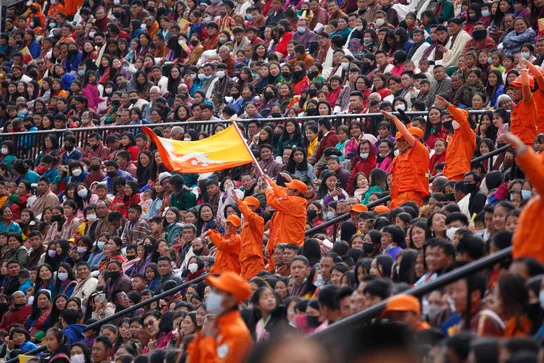 A crowd waving Bhutan's national flag during National Day celebrations